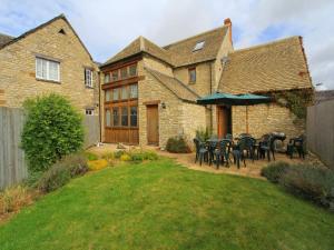 a house with a patio with tables and an umbrella at 6 Bed in Woodstock CC028 in Stonesfield