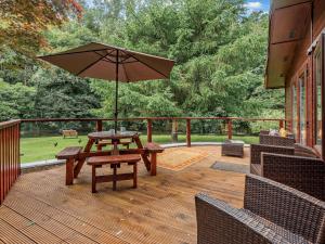 eine Holzterrasse mit einem Picknicktisch und einem Sonnenschirm in der Unterkunft 3 Bed in Cockermouth 49198 in Cockermouth