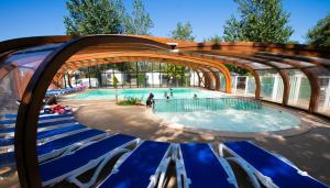 a swimming pool with blue chairs and an archway at Domaine de La Marina in Messanges