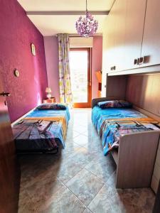 a bedroom with two beds and a pink wall at Roma e Castelli Romani. in Rome