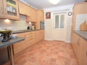 a kitchen with wooden cabinets and a tile floor at 1 Bed in Gilwern 52882 in Gilwern