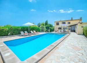 una piscina con sedie e ombrelloni accanto a una casa di Owl Booking Villa Alqueria Alt - Fantastic Mountain Views a Campanet