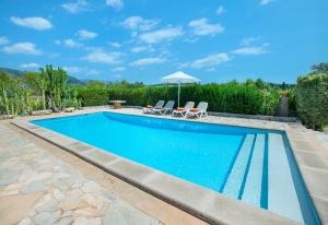 una piscina con due sedie e un ombrellone di Owl Booking Villa Alqueria Alt - Fantastic Mountain Views a Campanet