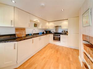 uma cozinha com armários brancos e piso em madeira em 3 bed property in Isle of Purbeck Dorset IC001 em Corfe Castle
