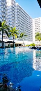 a swimming pool in front of a large building at Sea Residences, S, Shell Janine's Residency in Manila
