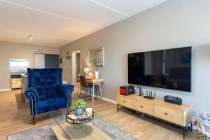 uma sala de estar com uma cadeira azul e uma televisão de ecrã grande em Nivica 56 Luxury Apartment Langebaan em Langebaan