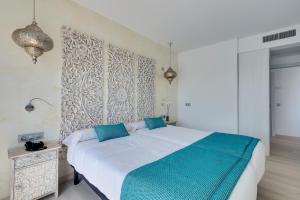 a bedroom with a large white bed with blue pillows at Cala Millor Garden Hotel - Adults Only in Cala Millor