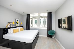 ein Schlafzimmer mit einem großen Bett und einem grünen Stuhl in der Unterkunft Staycity Aparthotels Liverpool Waterfront in Liverpool