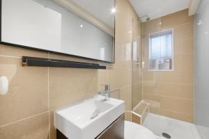 La salle de bains est pourvue d'un lavabo blanc et d'un miroir. dans l'établissement Modernised Apartments 1 and 2 Bedrooms Option Terrace and Balcony High Street, à Londres
