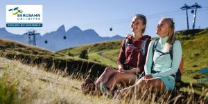 two people sitting on a hill in the grass at Komfort-Fewo "Allgäublick" - im südlichen Kurviertel nahe Therme, Wiesen - Bergbahnen unlimited Mai-Nov in Oberstdorf
