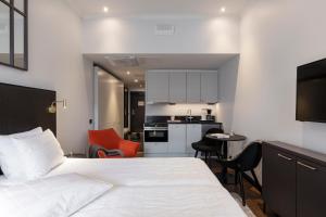 a bedroom with a white bed and a kitchen at Bob W Koti Katajanokka in Helsinki