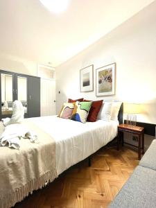 um quarto com uma grande cama branca com almofadas em kings cross St Pancras luxury apt em Londres
