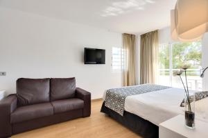 a bedroom with a couch and a bed and a window at Cala Millor Garden Hotel - Adults Only in Cala Millor