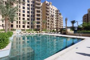 a swimming pool with palm trees and buildings at Livbnb - 2BR close to Souk Mall and Burj Al Arab in Dubai