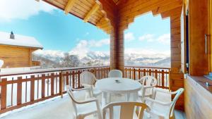 uma mesa e cadeiras numa varanda com vista em Fontannets COSY & MOUNTAIN chalets em Veysonnaz