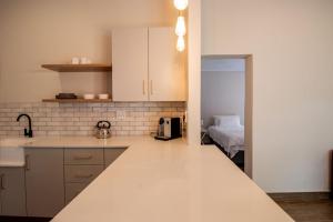 a kitchen with white cabinets and a bed in a room at De Vlei, Pretoria East in Pretoria