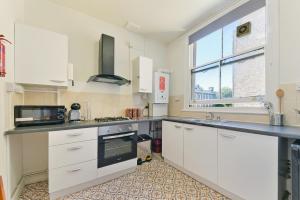 a kitchen with white cabinets and a sink and a microwave at Spacious Maida Vale 2 Bed Apartment in London