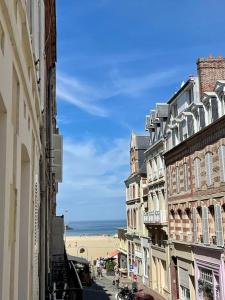 uma rua da cidade com edifícios e a praia ao fundo em Appartement à côté de la plage avec balcon filant em Trouville-sur-Mer