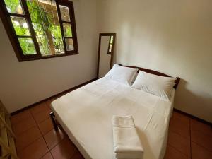 a bedroom with a white bed with a window at Nossa Guarda Acomodações in Guarda do Embaú