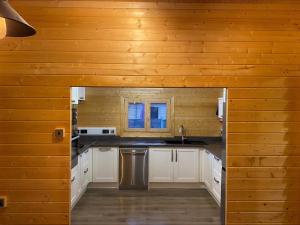 a kitchen with white cabinets and a wooden wall at Inviting 2-Bedroom Cabin in Ashton Under Hill in Evesham