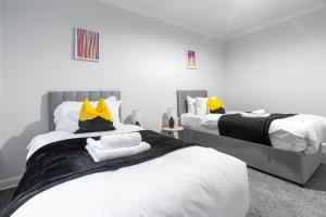 a bedroom with two beds with yellow and black pillows at Kirkview Apartment in Kirk of Shotts