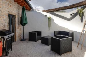 um pátio com 2 cadeiras, uma mesa e um guarda-sol em Casa da Broa - Recantos d'Almerinda 