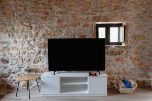una televisione su supporto bianco in una stanza con muro di mattoni di Casa da Broa - Recantos d'Almerinda 