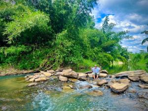 Ein Mann steht auf Felsen in einem Fluss in der Unterkunft Amano green resort in Ban Cha-om