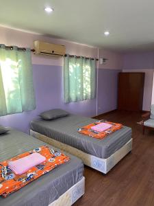 two beds in a room with purple walls at Amano green resort in Ban Cha-om