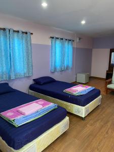 2 Betten in einem Zimmer mit blauen Vorhängen in der Unterkunft Amano green resort in Ban Cha-om