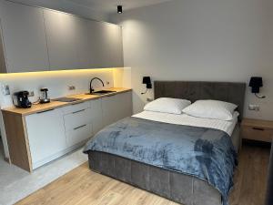 um quarto com uma cama e uma cozinha com armários brancos em Apartamenty WIERCHY em Klikuszowa