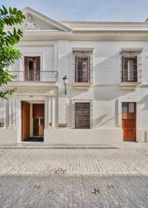 una casa blanca con una calle adoquinada delante en Hotel Mercer Sevilla en Sevilla