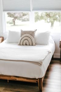 een bed met witte lakens en kussens voor een raam bij The Farm at Glenwood Mountain 