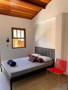 a bedroom with a bed and a red chair at Hostel Txai Juquehy Suítes in Juquei