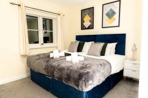 Un dormitorio con una gran cama azul con almohadas blancas en Livingston North Station Apartments en Livingston