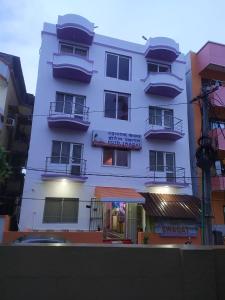 a white building with balconies on the side of it at Hotel Swagat in Puri