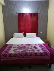 a bedroom with a large bed with a purple blanket at Hotel Swagat in Puri