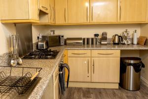 cocina con armarios de madera y horno con fogones en Livingston North Station Apartments en Livingston
