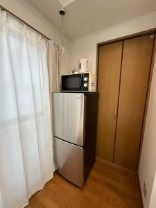 a kitchen with a refrigerator with a microwave on top of it at Minato Shibaura-404 in Tokyo