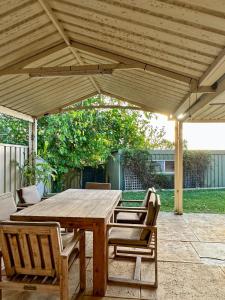 a wooden table and chairs under a wooden pergola at Family Home Close To All Perth Adventures in Hamilton Hill