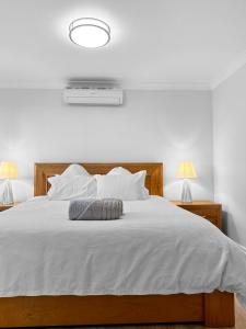 a bedroom with a white bed with two lamps at Family Home Close To All Perth Adventures in Hamilton Hill