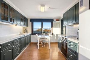 a kitchen with green cabinets and a table and a window at Island Getaway: Sea and Mountain Views in Ålesund