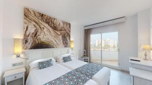 una camera d'albergo con un letto e una grande finestra di Cala Millor Garden Hotel - Adults Only a Cala Millor