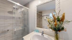 a bathroom with a sink with a mirror and a vase of flowers at Cala Millor Garden Hotel - Adults Only in Cala Millor
