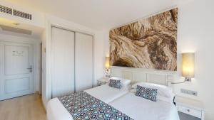 カラ・ミラーにあるCala Millor Garden Hotel - Adults Onlyのベッドルーム1室(ベッド1台付)が備わります。壁には絵画が飾られています。