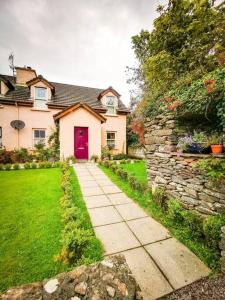 una casa con una puerta roja y una pared de piedra en Orchard Cottage, en Dingle