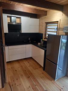 a kitchen with white cabinets and a black refrigerator at Domek pod Śnieżką 2 in Miłków
