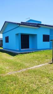 a blue house with a grass field in front of it at Paraíso tropical in Balneário Gaivotas
