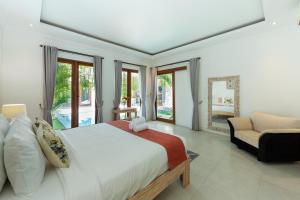 a bedroom with a bed and a couch and windows at Deby Villa Seminyak in Seminyak