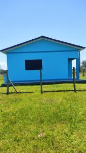 a blue building with a sign in the grass at Paraíso tropical in Balneário Gaivotas